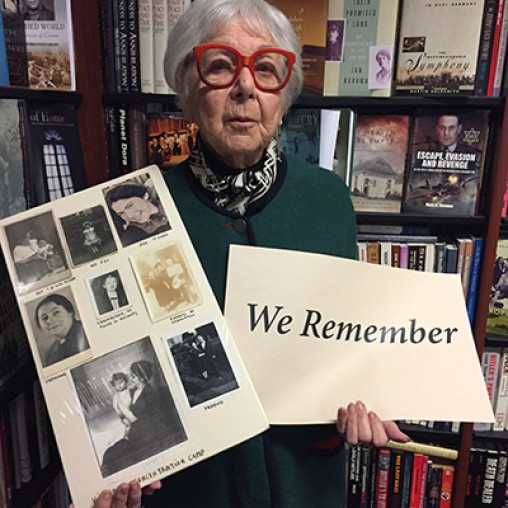 holocaust survivor holding sign that says we remembers and photos of family