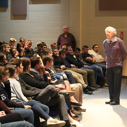 holocaust survivor speaking to a group of students in an auditorium 