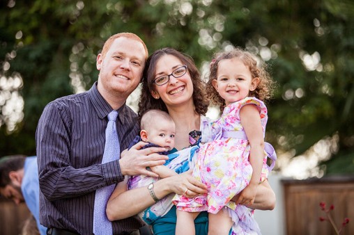 A mother and father smiling holding their two young children