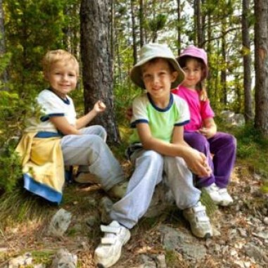 Three young campers sitting in front of a tree