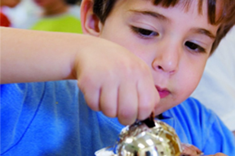 Boy putting coins in a tzedaka box