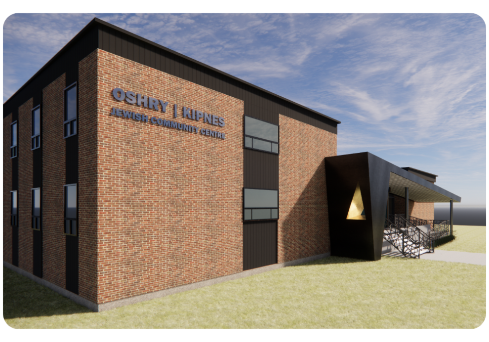 A modern brick building with a black accent, featuring the sign "OSHRY | KIPNES JEWISH COMMUNITY CENTRE" on the front, surrounded by grass and a clear sky.