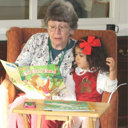 Little girl listening to a story being read by an older woman null
