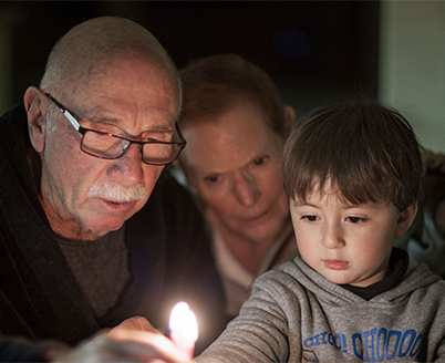 Grandparents lighting a candle with their grandson