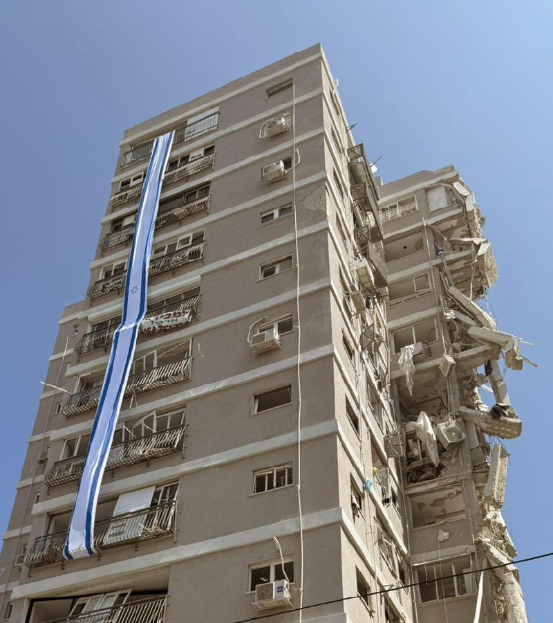 A damaged building with an Israeli flag on the side