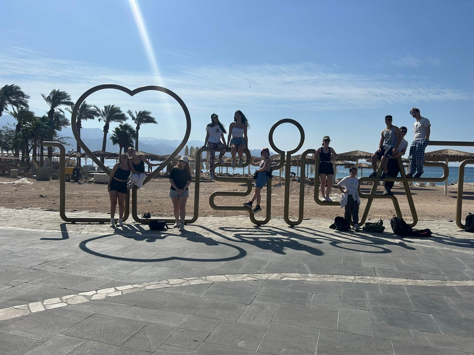 Teens in Israel around an eilat sign